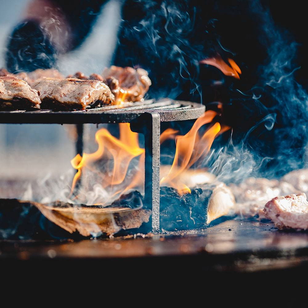 Kød grilles over åben ild på rund havegrill
