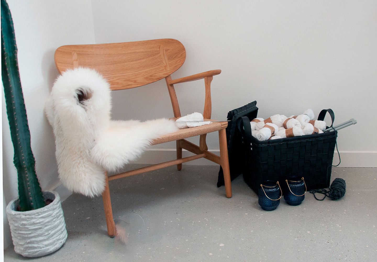 Træstol med hvidt lammeskind ved opbevaringskurv