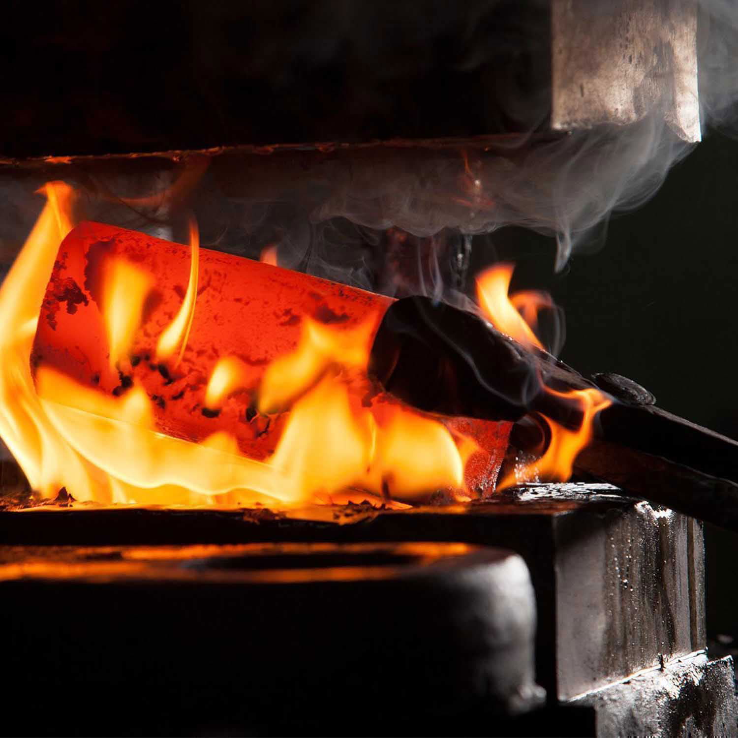 Glødende stål opvarmes i esse med flammer