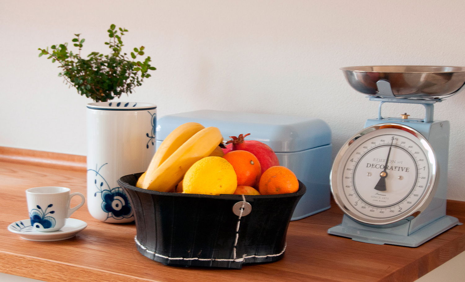 Retro køkkenvægt, frugtkurv og porcelæn på bord
