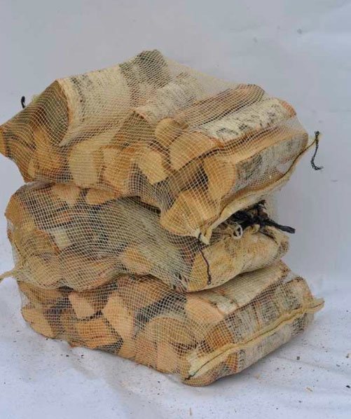 Tre netposer med kløvet brænde stablet